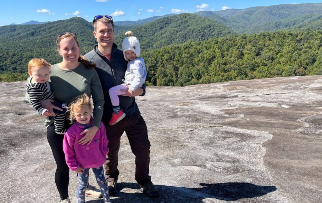 Emily fedel and her family standing together on top of a large rock